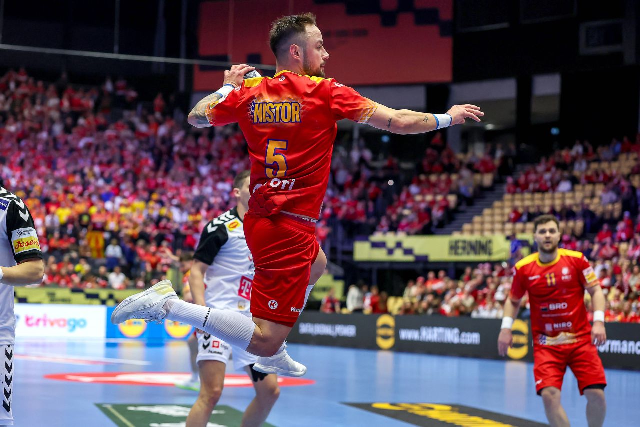Mihai Popescu, portarul României, ridicând trofeul MVP la EHF EURO 2026, în fața clasamentului naționalei România. | sursa foto: Sport.ro Mihai Popescu, portarul României, ridicând trofeul MVP la EHF EURO 2026, în fața clasamentului naționalei România. | sursa foto: Sport.ro