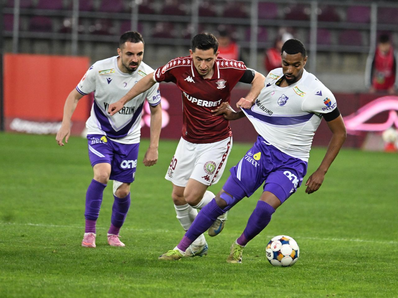 Jucători de fotbal pe teren în timpul unui meci din play-off fotbal, cu afișarea licenței UEFA afectată de datorii cluburi. | sursa foto: Sport.ro Jucători de fotbal pe teren în timpul unui meci din play-off fotbal, cu afișarea licenței UEFA afectată de datorii cluburi. | sursa foto: Sport.ro